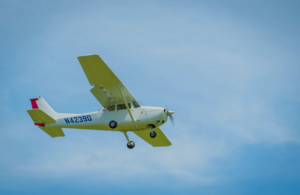 Single-engine training aircraft flies through a blue sky with landing gear extended and registration number N42390 visible on the fuselage.