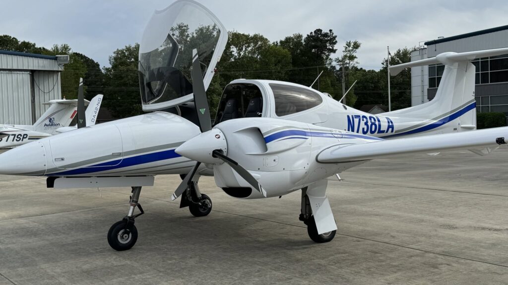 Diamond training aircraft parked on an airport ramp with its canopy open, showcasing a modern cockpit and the registration number N738LA.