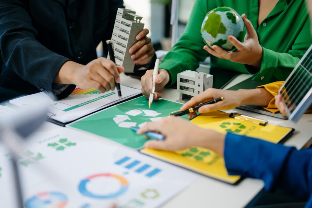 An eye-level shot shows a meeting taking place at a white table, focusing on sustainable building and renewable energy.