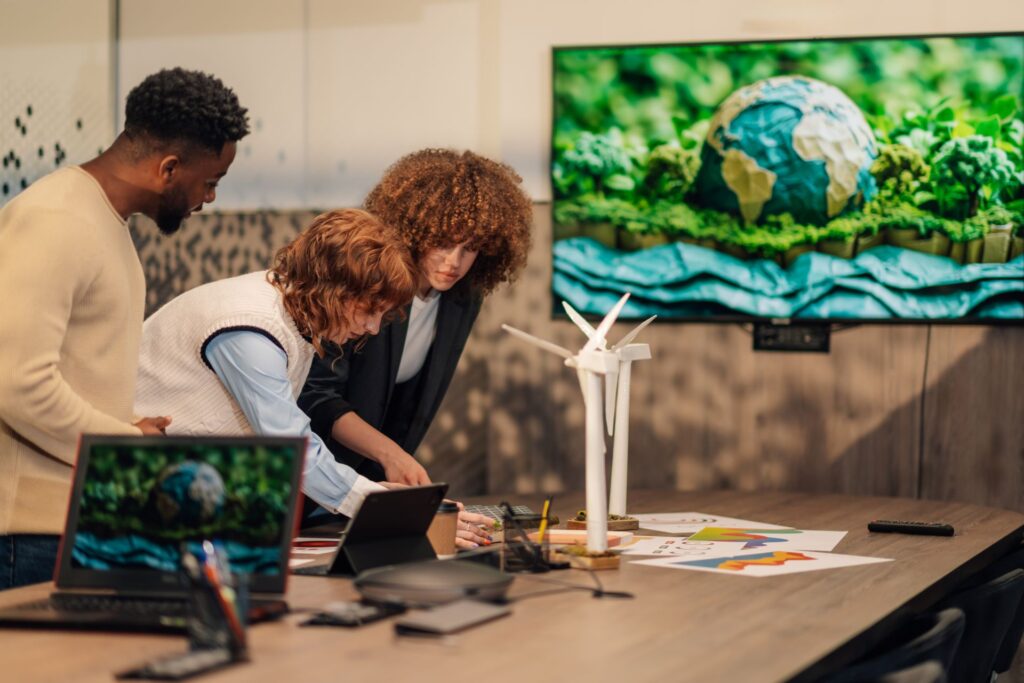 In a well-lit meeting room, a trio of individuals gather around a table, their attention focused on a shared project.