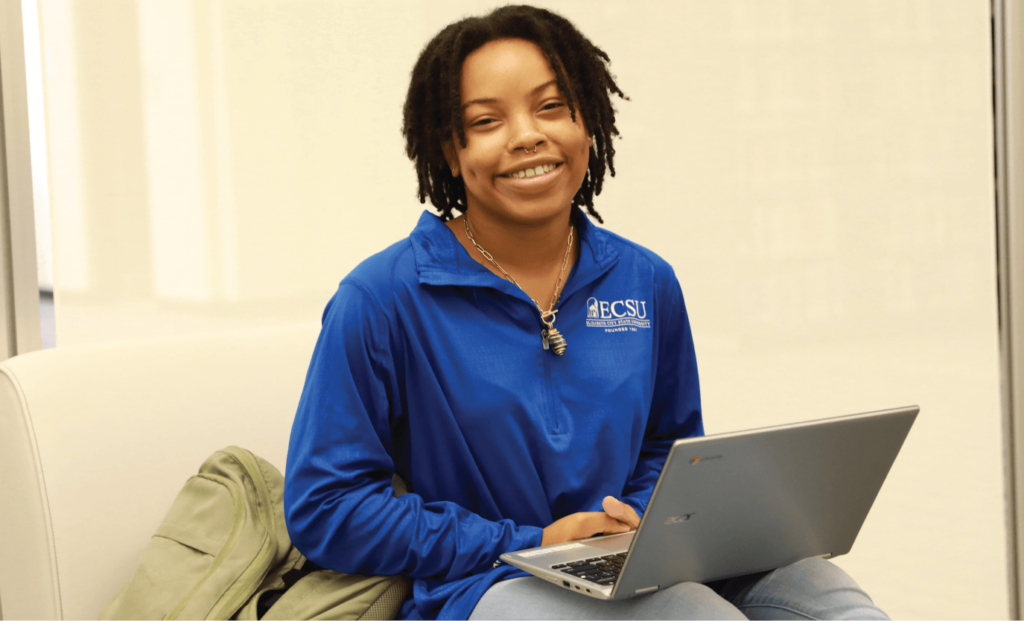 Student smiling at camera with laptop in lap