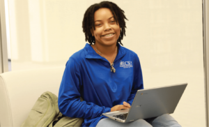 Student smiling at camera with laptop in lap