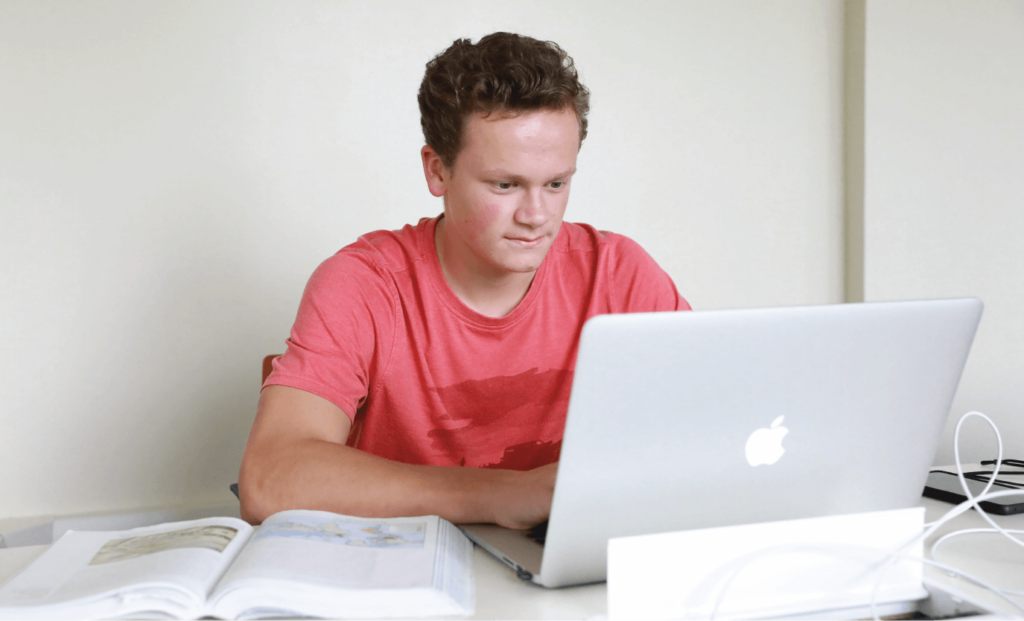 Student on laptop and open book