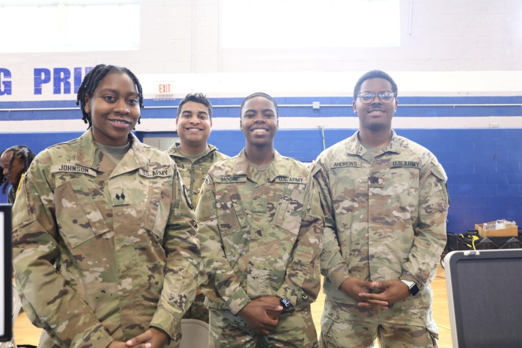 Four ECSU ROTC students smiling at the camera with hands clasped in front of them.