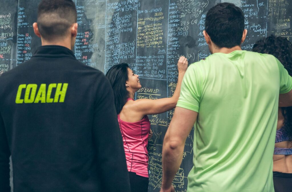 Three adults stand in front of a chalkboard covered with equations and work out information. 