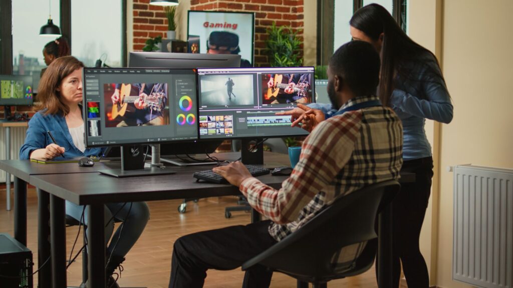 In a brightly lit office, three adults collaborate on video editing.