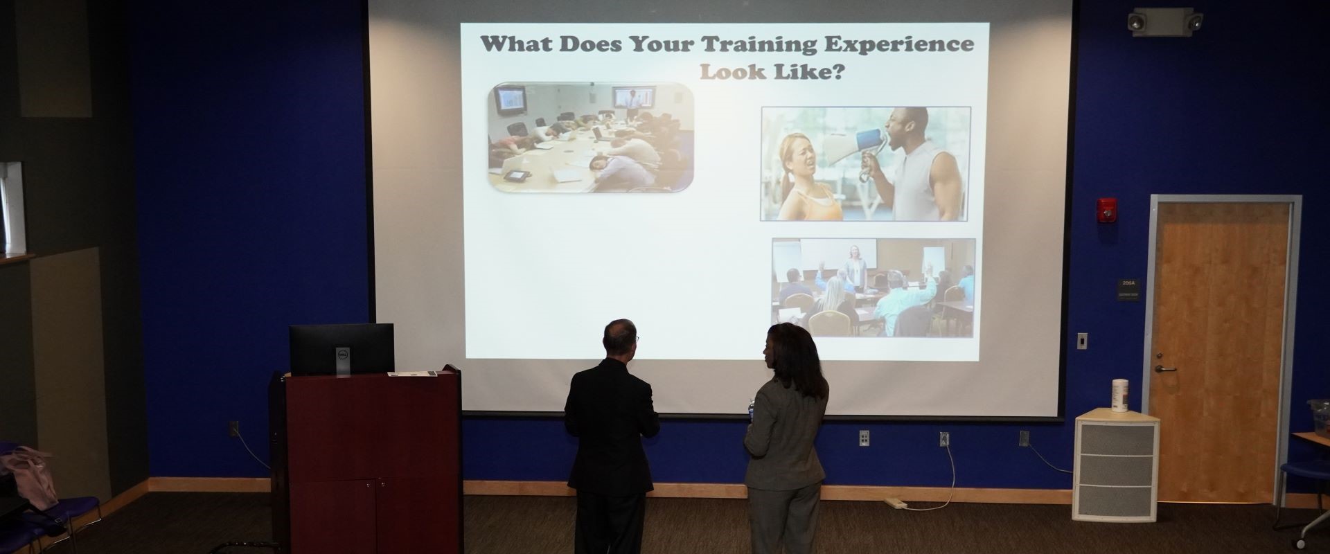 Presenter in lecture hall with a presentation being projected.