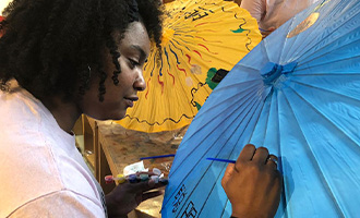 ECSU student painting a blue paper umbrella