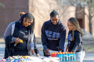 A group of ECSU students doing an activity at a table set up outside, on campus.