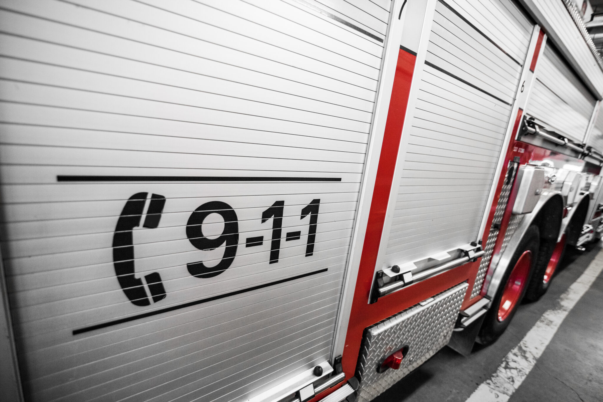 A detailed view showcases the side of an emergency services vehicle featuring the prominent black 9-1-1 graphic and red stripes.