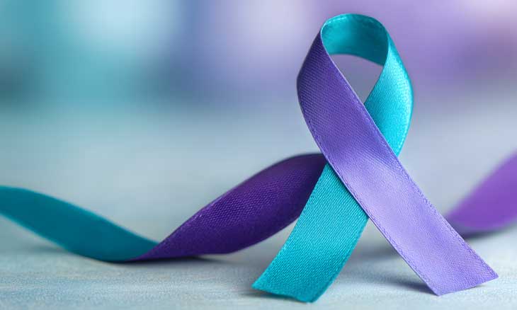Purple and teal awareness ribbon arranged in a loop on a soft surface, symbolizing suicide prevention and mental health awareness.