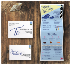Wedding invitation suite featuring a coastal theme with lighthouse and ocean wave illustrations. The design includes a fold-out invitation, RSVP card, mailing pieces, accommodation information, menu selections, and event details presented in a blue-and-white color palette on a wood-textured background.