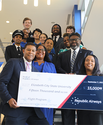 ECSU students and representatives from Republic Airways hold a $15,000 scholarship award check supporting the university's Flight Program.